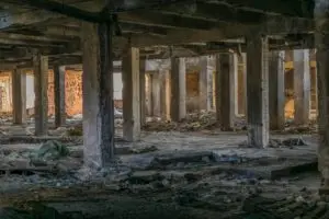 Abandoned industrial space with dilapidated columns and scattered debris, enveloped in a quiet atmosphere.